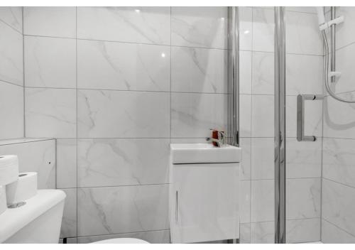 a white bathroom with a shower and a toilet at Serene Bliss: Perfect Studio For 2 in London