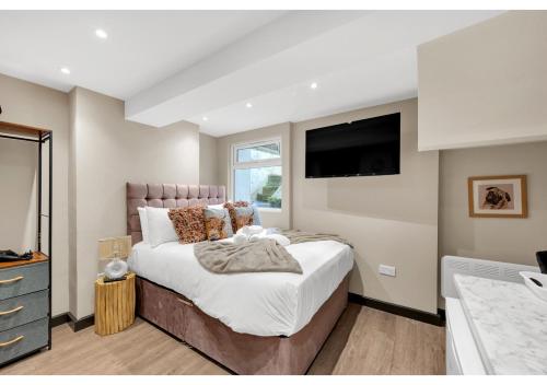 a bedroom with a large bed and a flat screen tv at Serene Bliss: Perfect Studio For 2 in London