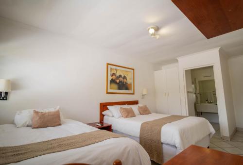 a hotel room with two beds and a mirror at Broadway Boston in Cape Town