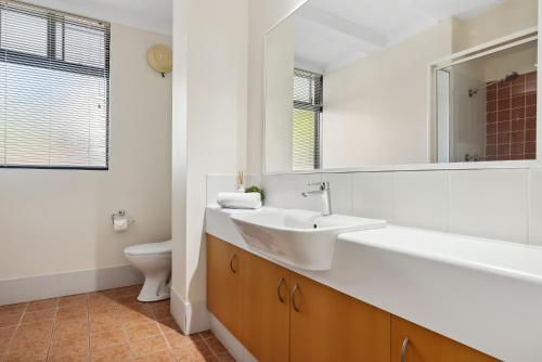uma casa de banho com um lavatório, um espelho e um WC. em Riverside Elegance Central 1BR 1BA Apartment em Perth