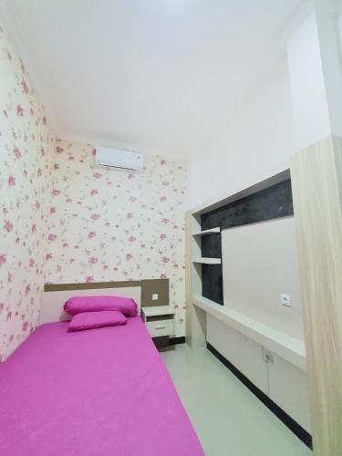 a bedroom with a purple bed and a flat screen tv at Kos Harian Wisma Selma Garuda in Kejayan