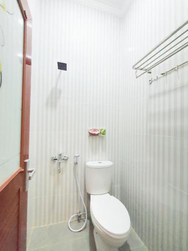 a white bathroom with a toilet and a shower at Kos Harian Wisma Selma Garuda in Kejayan