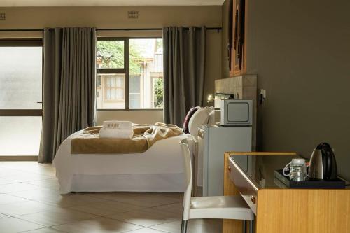 a bedroom with a bed and a refrigerator and a window at Kuruman Lodge in Kuruman