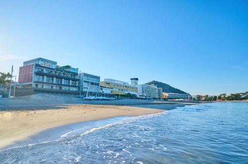ein Strand mit einigen Gebäuden und dem Wasser in der Unterkunft Scapes The Suite in Hayama