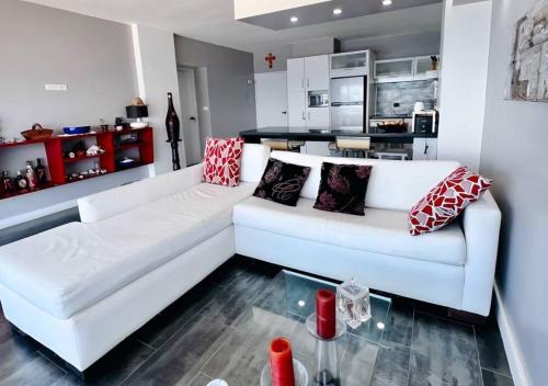 uma sala de estar com um sofá branco com almofadas em Suite Coco CarIbe em Porlamar