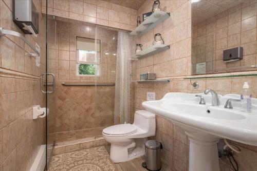 a bathroom with a sink and a toilet and a shower at Abbey House in Massapequa