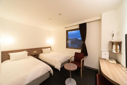 a hotel room with two beds and a window at Business Hotel Ueno in Yamaguchi