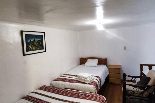Habitación pequeña con 2 camas y silla en Q'osqo Apartments, en Cusco