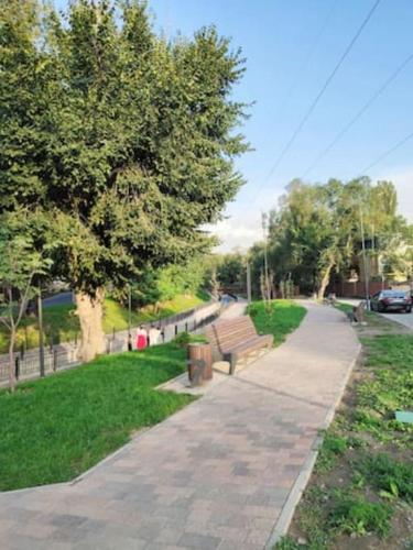 a park with a bench and a sidewalk and trees at Уютное место в центре городА in Almaty