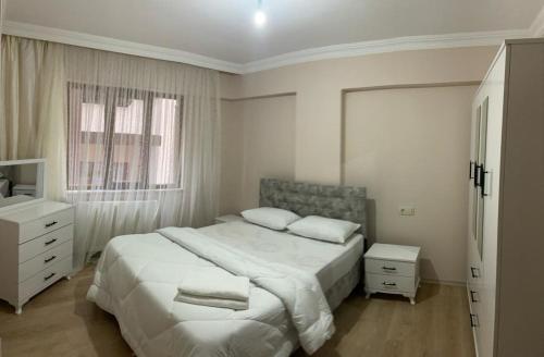a white bedroom with a large bed and a window at Ecemsuit2 in Yomra