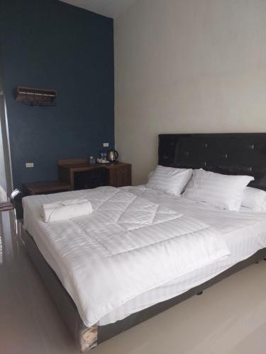 Kala Guest House في Kabanjahe: سرير أبيض كبير مع ملاءات ووسائد بيضاء