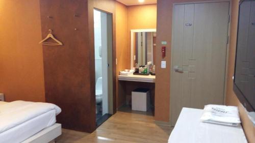 a bedroom with a bed and a bathroom with a sink at Residence R Hotel in Daegu