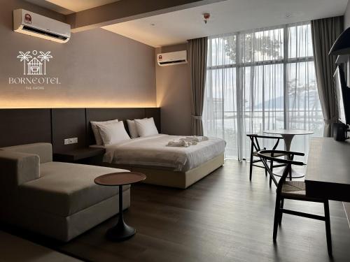 a hotel room with two beds and a couch at Borneotel The Shore KK by CHG in Kota Kinabalu