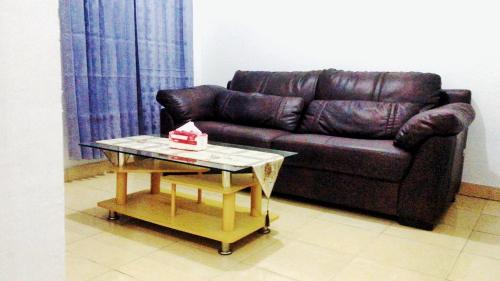 a living room with a brown leather couch and a table at Baronda Guest House in Sorong