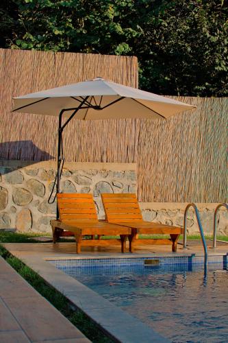an umbrella and two benches next to a swimming pool at Sapanca Grandwooden in Sakarya