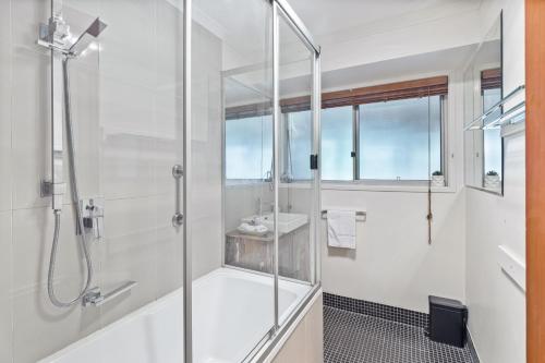 a white bathroom with a shower and a sink at A heavenly haven in Maleny in Maleny