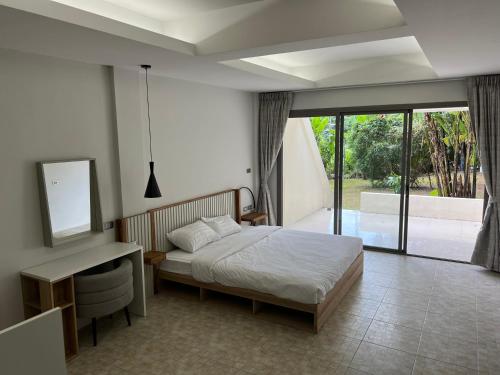 1 dormitorio con cama y escritorio con espejo en The Green Golf Apartments en Ban Thung Thong