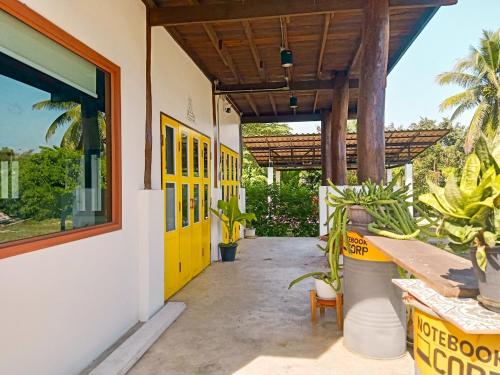 un edificio con una puerta amarilla y algunas plantas en ต้นผึ้ง แอทโฮม, en Ban Nong Sae
