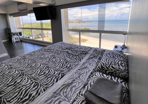 a zebra print bed in a bedroom with a view of the beach at Suite Coco CarIbe in Porlamar