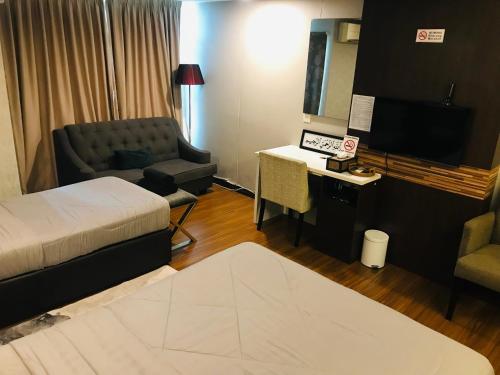 a hotel room with a bed and a couch and a television at FirIzzkey Studio in Kota Bharu
