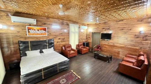 a bedroom with a bed and two chairs and a television at Homewood Suites And Guest House in Jammu