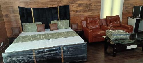 a bedroom with a bed and two chairs at Homewood Suites And Guest House in Jammu