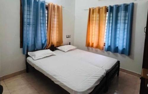a bedroom with a large bed with blue curtains at OYO GoodInn Apartment in Elūr