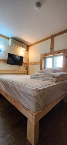 a large wooden bed in a room with a tv at Mizo Hotel in Seoul
