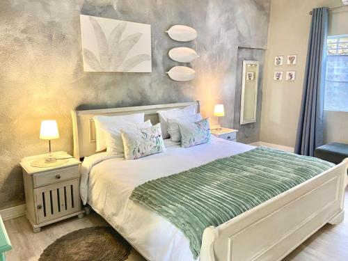 een slaapkamer met een wit bed en een groene deken bij Selah Guest Cottages Self-catering Farmstay Accommodation in Nelspruit