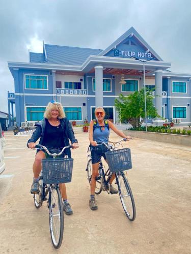 two women riding bikes in front of a hotel at Tulip Hotel in Louang Namtha