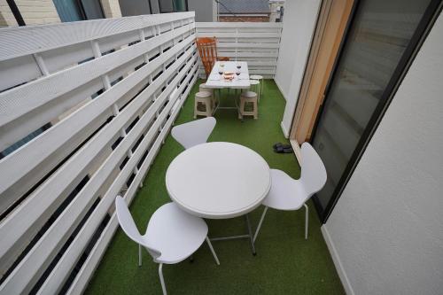 einen kleinen Balkon mit einem weißen Tisch und Stühlen in der Unterkunft Soo Guest House in Seoul