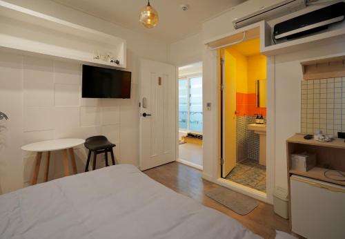 a bedroom with a bed and a table and a bathroom at Soo Guest House in Seoul