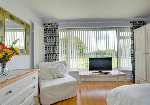 a bedroom with a bed and a tv and a chair at Sandy Reach ( Croft Court ) in Tenby