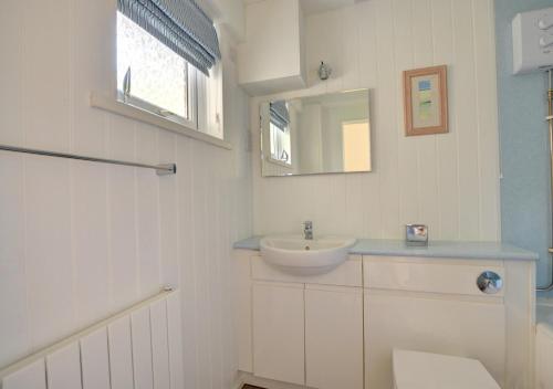 a white bathroom with a sink and a mirror at Sandy Reach ( Croft Court ) in Tenby