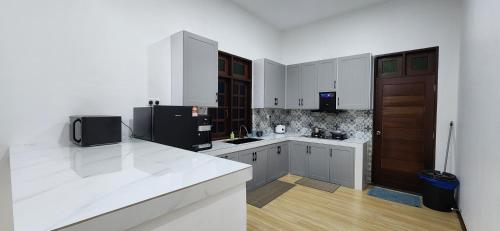 uma cozinha com armários brancos e um frigorífico preto em Najazi Villa em Setiu