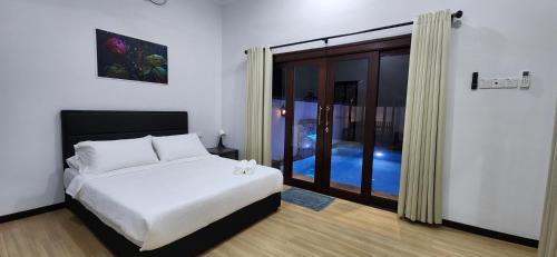 a bedroom with a bed and a large window at Najazi Villa in Setiu