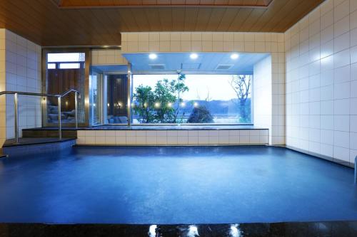 a swimming pool with a blue floor and a window at Okukinosaki Seaside Hotel in Toyooka