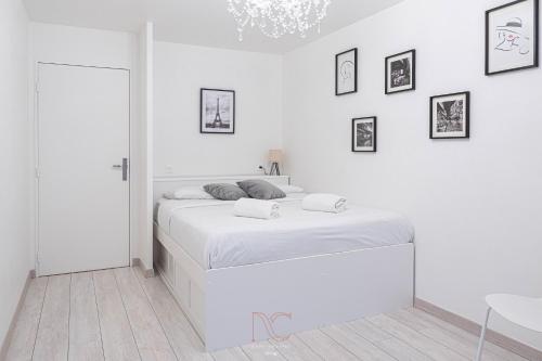 a white bedroom with a bed and a chandelier at *Disneyland-Paris* 4pers, Parking, Wifi in Chessy