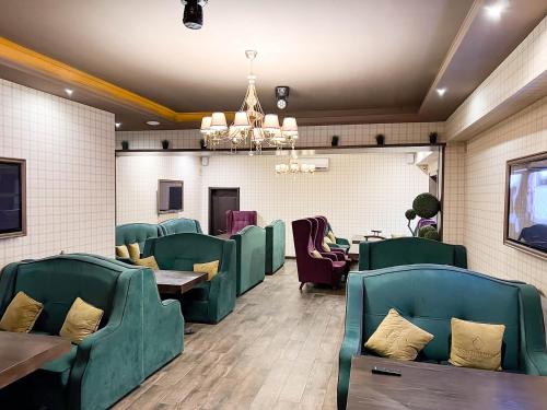 ein Restaurant mit grünen Stühlen, Tischen und einem Kronleuchter in der Unterkunft REIKARTZ PARK ASTANA ex-Royal Park Hotel & SPA in Astana