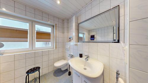a white bathroom with a sink and a mirror at Ferienhaus Hoffmann am Rheinbogen in Altlußheim