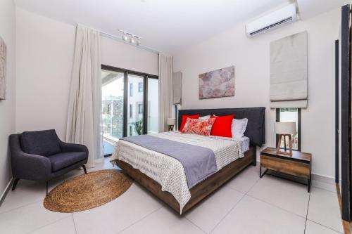 a bedroom with a bed and a chair and a window at Brand new, Beachfront Ocean Terraces, Poste Lafayette-Apt-C4 in Poste Lafayette