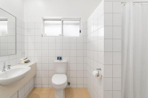 a white bathroom with a toilet and a sink at Comfort Inn The International in Apollo Bay