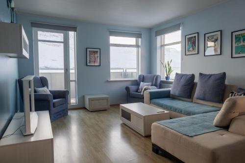 a living room with blue walls and a couch and chairs at Hildibrand Apartment Hotel in Neskaupstaður