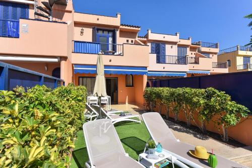a patio with lawn chairs and an umbrella and a building at Duplex Bahia Meloneras 47 by VillaGranCanaria in Meloneras