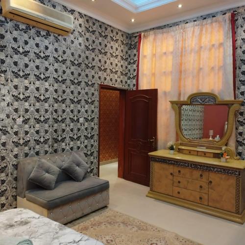 een slaapkamer met een spiegel, een stoel en een dressoir bij العين الهيلي مصباح بيت14 in Al Ain