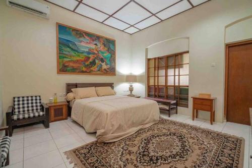 een slaapkamer met een bed en een schilderij aan de muur bij Veranda Java - Traditional & Modern Javanese Villa in Godean