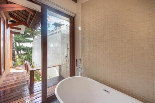 a bathroom with a tub and a large window at L'Osteria Luxe Beachfront B&B in General Luna