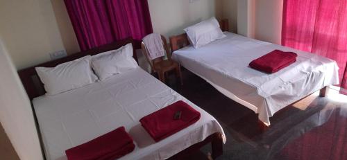 two beds in a room with red pillows on them at Gokarna Govekar Sea Facing Rooms in Gokarn