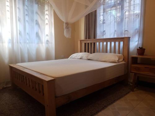 ein Bett mit einem Holzrahmen und einem Fenster in der Unterkunft Avacado Homestay in Arusha