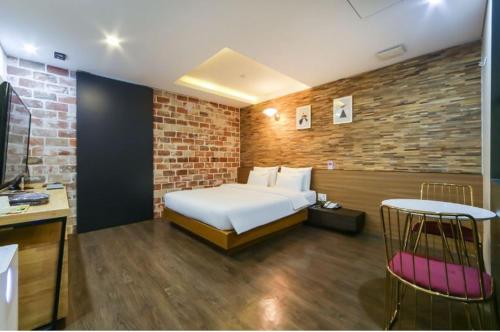 a bedroom with a white bed and a brick wall at Stay 247 in Gimhae